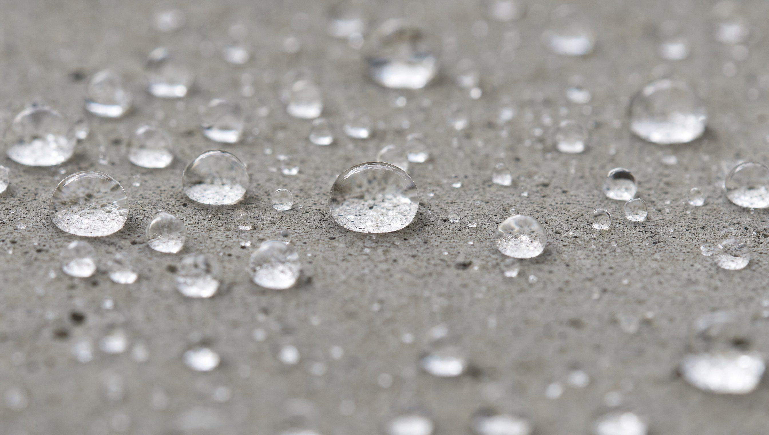 Wassertropfen perlen auf einer beschichteten Betonoberfläche ab